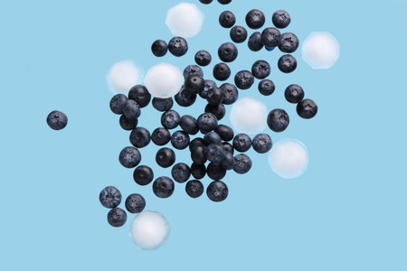 Flying sweet fresh blueberries and ice cubes on blue backgroundの写真素材