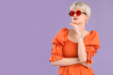 Portrait of thoughtful young woman with sunglasses on lilac backgroundの写真素材