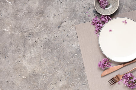 Beautiful table setting with lilac flowers on gray grunge backgroundの写真素材