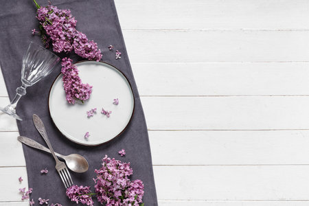 Beautiful table setting with lilac flowers on white wooden backgroundの写真素材