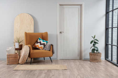 Minimalist interior of living room with brown armchair, cushion, rattan box and doorの写真素材