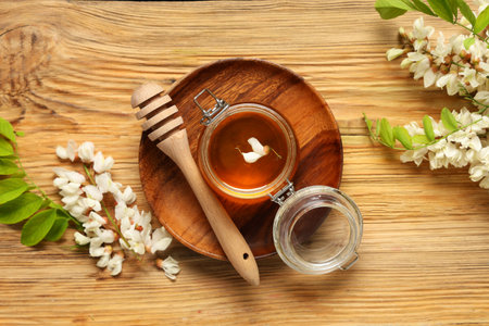 Jar of sweet honey with acacia flowers and dipper on wooden backgroundの写真素材
