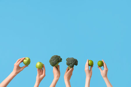 Hands holding green apples and broccoli on blue backgroundの写真素材