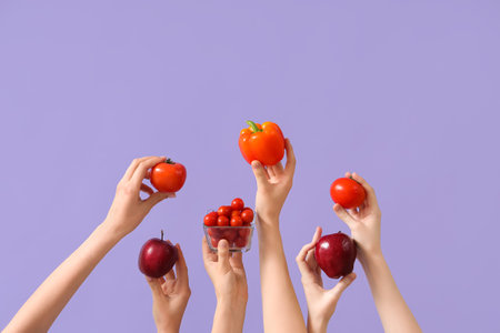 Hands with fresh tomatoes, apples and bell peppers on lilac backgroundの写真素材