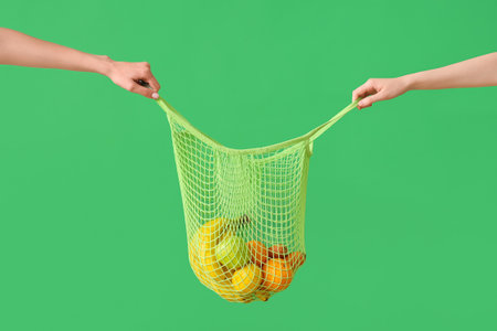Hands holding bag with fresh fruits on green backgroundの写真素材