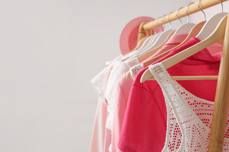Rack with hanging clothes near pink wallの写真素材