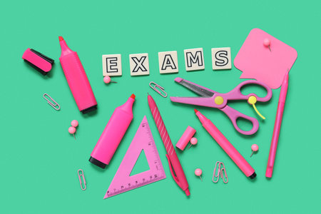 Composition with word EXAMS and bright stationery on green background