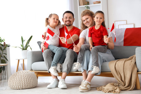 Happy family with flags of Canada sitting on sofa at homeの写真素材