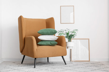 Comfortable armchair with stack of pillows near white wallの写真素材
