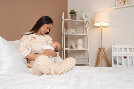 Mother breastfeeding her baby in bedroomの写真素材