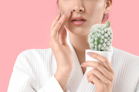 Beautiful young shocked woman with cactus on pink background, closeup. Depilation conceptの写真素材