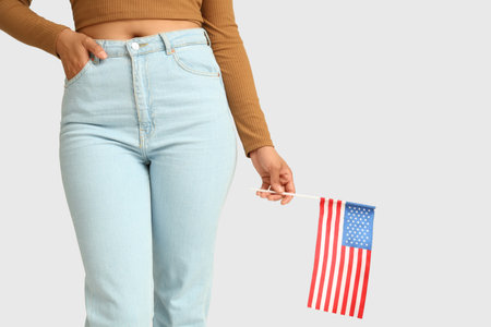 Beautiful young African-American woman with USA flag on white background, closeupの写真素材