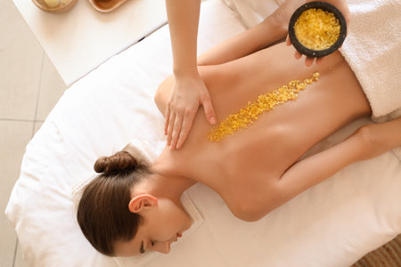 Young woman getting back massage with sea salt on couch in spa salon, top viewの写真素材