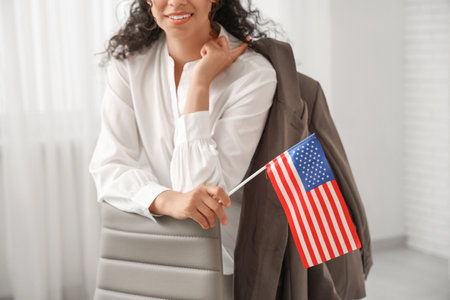 Beautiful young happy African-American businesswoman with USA flag in office, closeupの写真素材