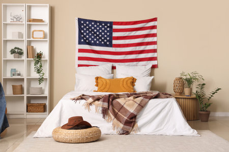 USA flag and comfortable bed in interior of bedroomの写真素材