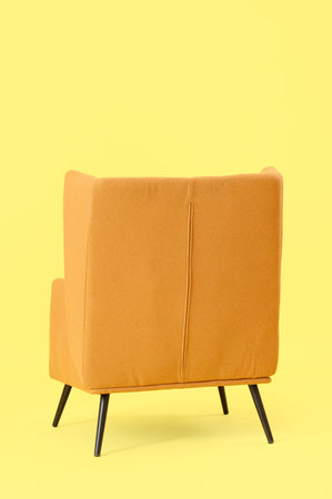 Brown armchair on yellow background. Back viewの写真素材