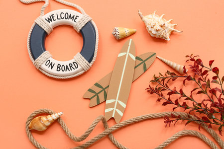 Rope, surf boards, lifebuoy ring and seashells on orange background. Summer concept