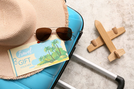 Suitcase with beach accessories, travel gift voucher and wooden plane on grunge background, closeupの写真素材
