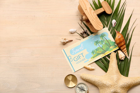 Composition with travel gift voucher, seashells, vintage compass and palm leaf on wooden backgroundの写真素材