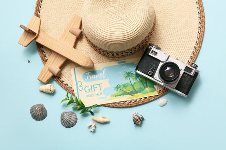 Composition with travel gift voucher, photo camera, stylish straw hat and wooden plane on color backgroundの写真素材