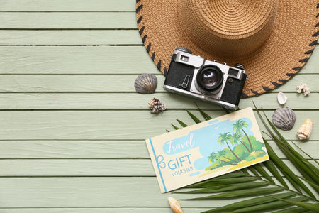 Composition with travel gift voucher, photo camera, straw hat and palm leaf on color wooden backgroundの写真素材