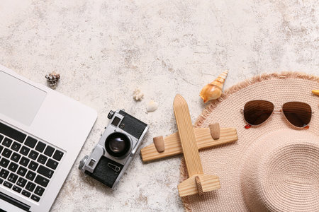 Composition with wooden plane, laptop, photo camera and beach accessories on light backgroundの写真素材