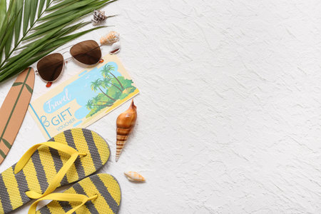 Composition with travel gift voucher, beach accessories and palm leaf on light backgroundの写真素材