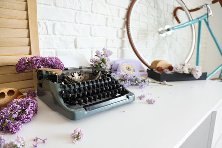 Vintage typewriter with lilac flowers on table in author's office, closeupの写真素材