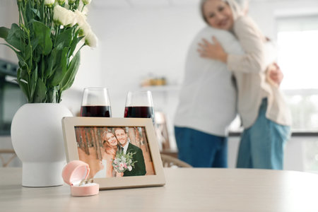 Picture of couple celebrating their wedding anniversary with rings and wine on table in kitchenの写真素材