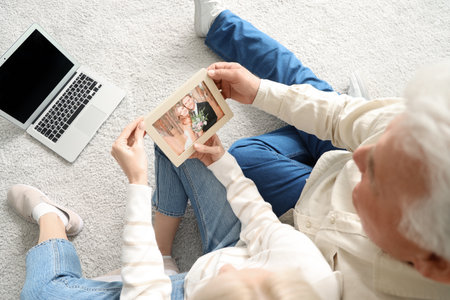 Mature couple with photo frame celebrating their wedding anniversary at home, top viewの写真素材