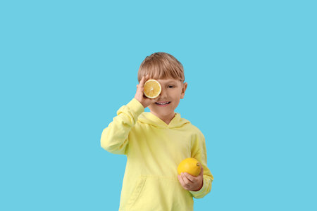 Cute little boy with lemon on blue backgroundの写真素材