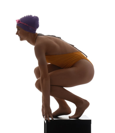 Young female swimmer on springboard against white backgroundの写真素材