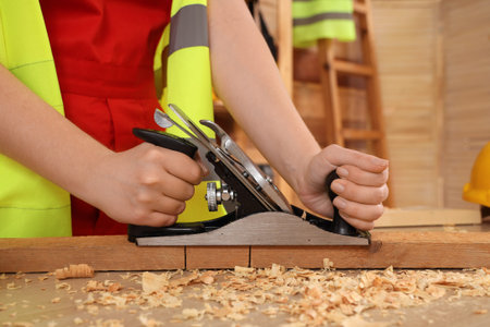 Female carpenter planning plank in workshop, closeup. Labor Day celebration
