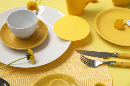 Beautiful table setting with dandelion flowers on yellow backgroundの写真素材