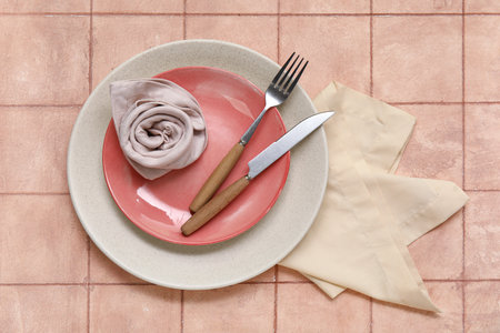 Beautiful table setting with flower made of napkin and envelope on beige tile backgroundの写真素材