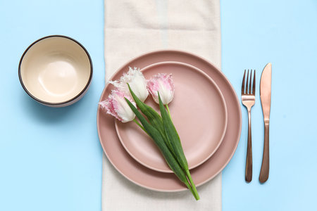 Stylish table setting with beautiful tulips on blue backgroundの写真素材