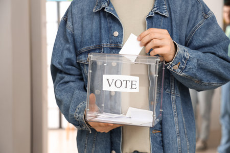 Voting young man with ballot box at polling station, closeupの写真素材
