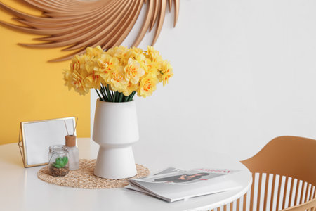 Chairs and table with bouquet of daffodil flowers in living roomの写真素材