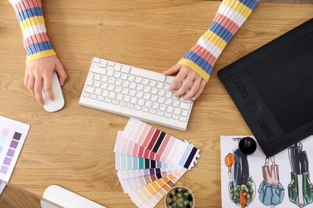 Female graphic designer working with computer at table in office, top view