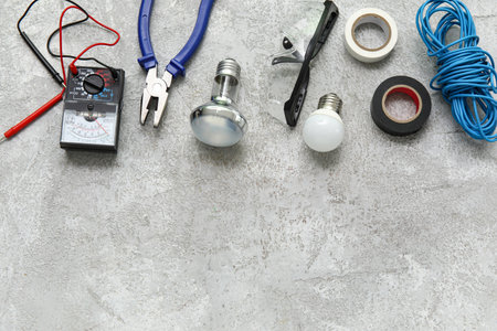 Electrician's tools and light bulbs on gray grunge backgroundの写真素材