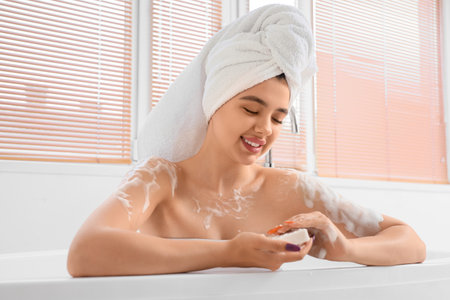 Young woman with soap taking bath at home