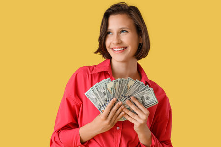 Pretty young woman with money on yellow background