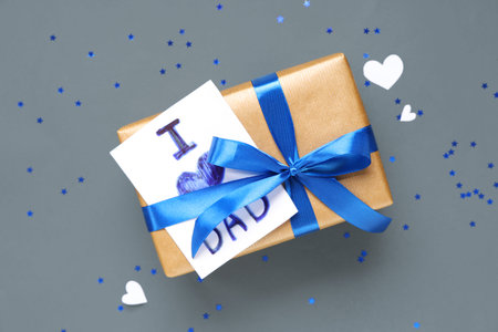 Gift box and paper with text I LOVE DAD on gray background. Father's day celebration. Top view
