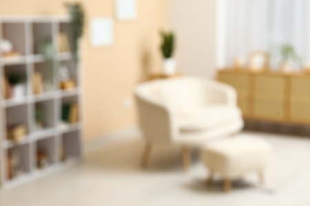 Bookcase with books and houseplants near white sofa in stylish living room, blurred viewの写真素材