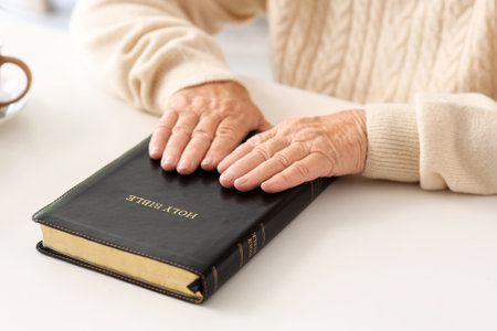 Senior woman with Bible sitting at table in living room, closeupの写真素材