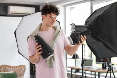 Happy male photographer with professional equipment in studio