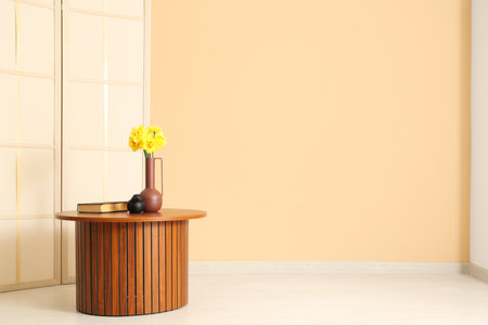 Vase with daffodil flowers on table with book in living roomの写真素材