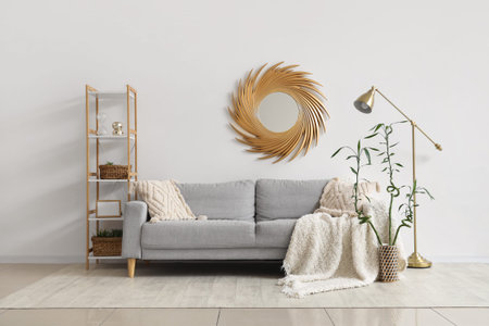 Interior of living room with cozy sofa with plaid, lamp and mirror