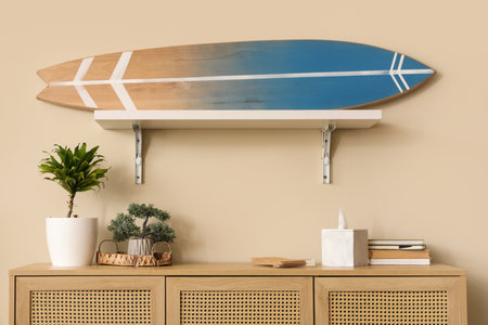 Surfboard on wall and different decor on chest of drawers in living roomの写真素材
