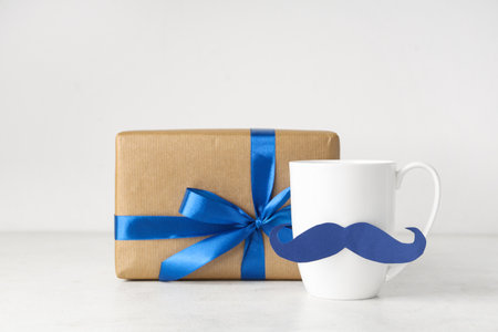 Paper mustache on cup and gift box on white background. Father's Day celebrationの写真素材